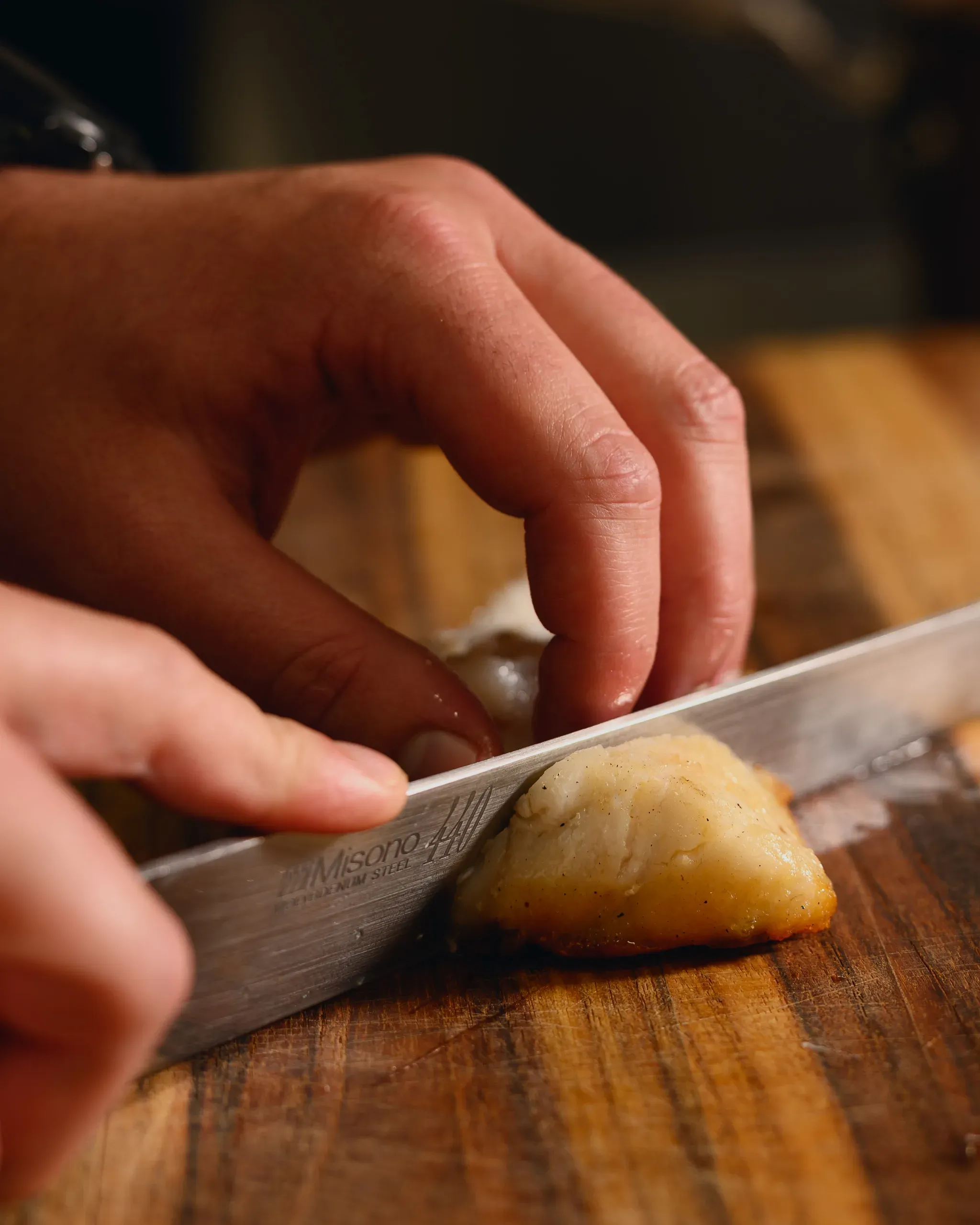 Chef slicing seared monkfish on a wooden board at Salt, The Ritz-Carlton Amelia Island